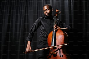 Un uomo in camicia nera tiene in mano un violoncello