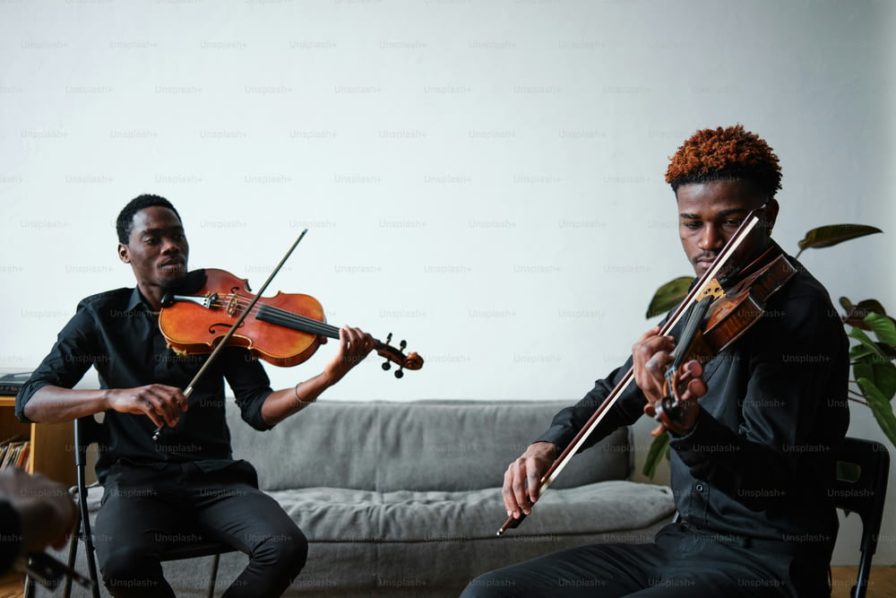 Dos hombres tocando el violín en una sala de estar