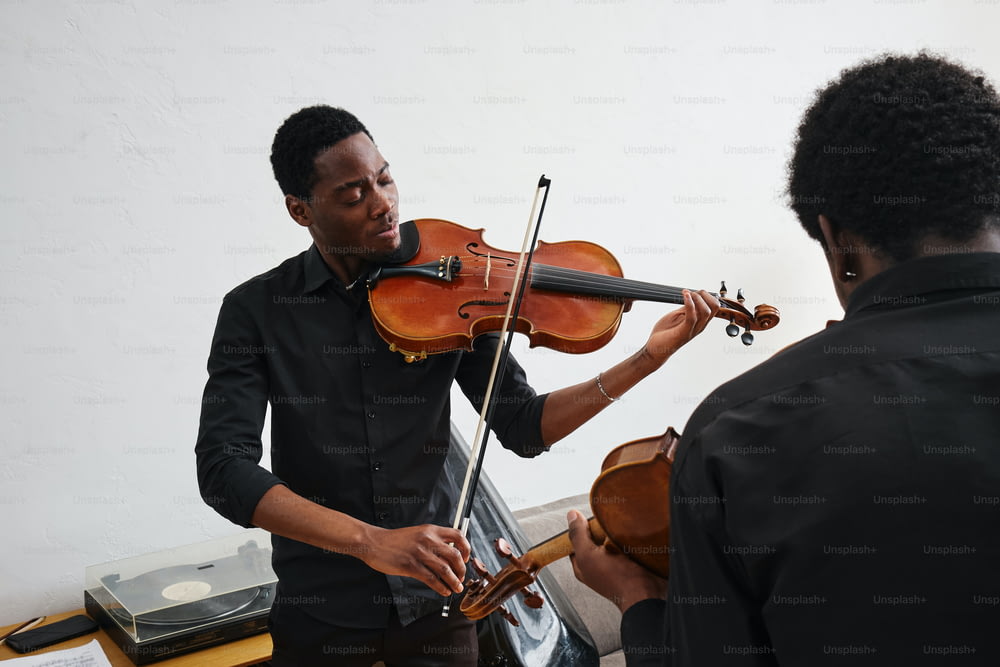 un hombre tocando un violín mientras otro hombre observa