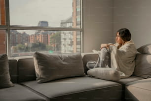 una donna seduta su un divano che guarda fuori da una finestra