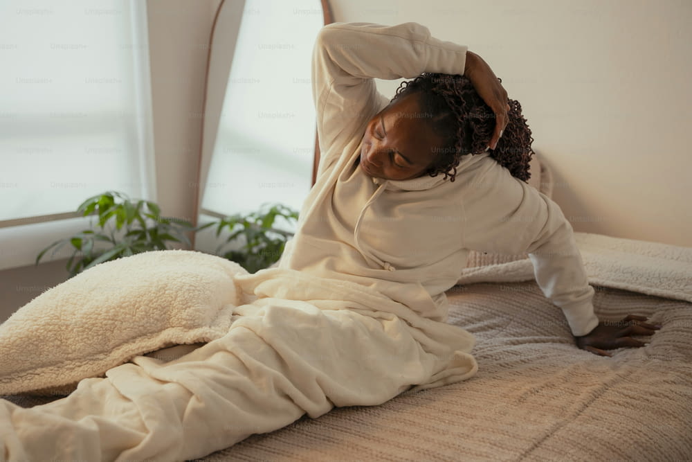 una donna sdraiata sopra un letto coperta da una coperta