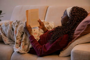 una donna seduta su un divano che legge un libro