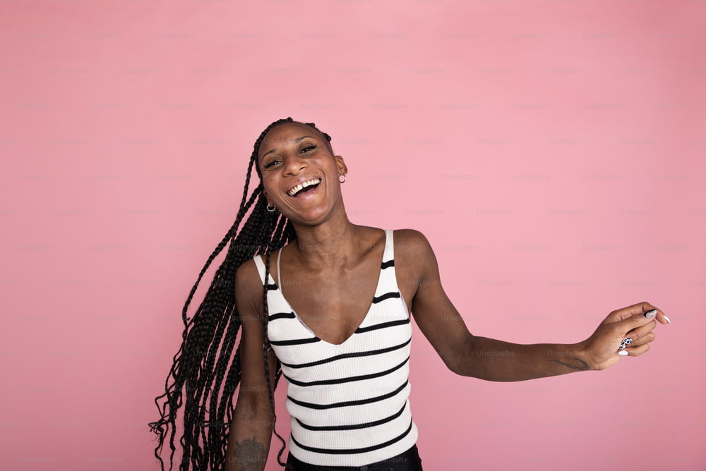 a woman with dreadlocks standing in front of a pink background