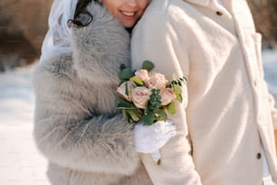 a bride and groom hugging each other in the snow