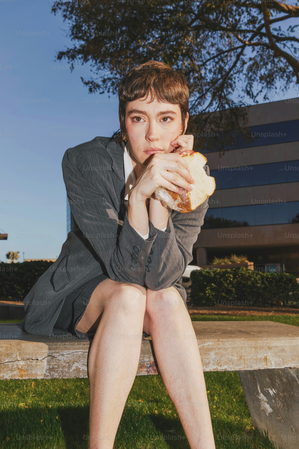 une femme assise sur un banc en train de manger un sandwich
