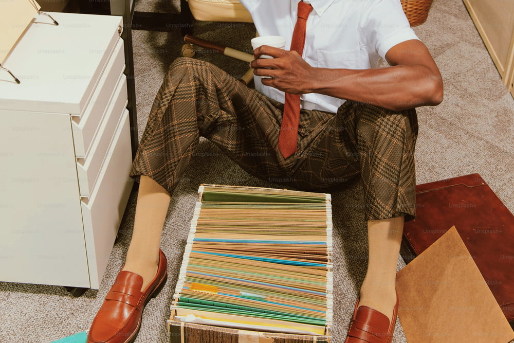 Ein Mann sitzt auf dem Boden neben einem Stapel Papiere