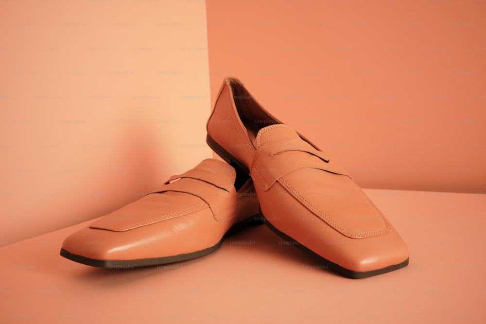 une paire de chaussures beige posée sur un sol rose