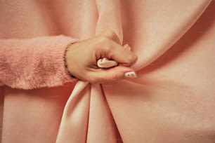 ピンクの布地に女性の手