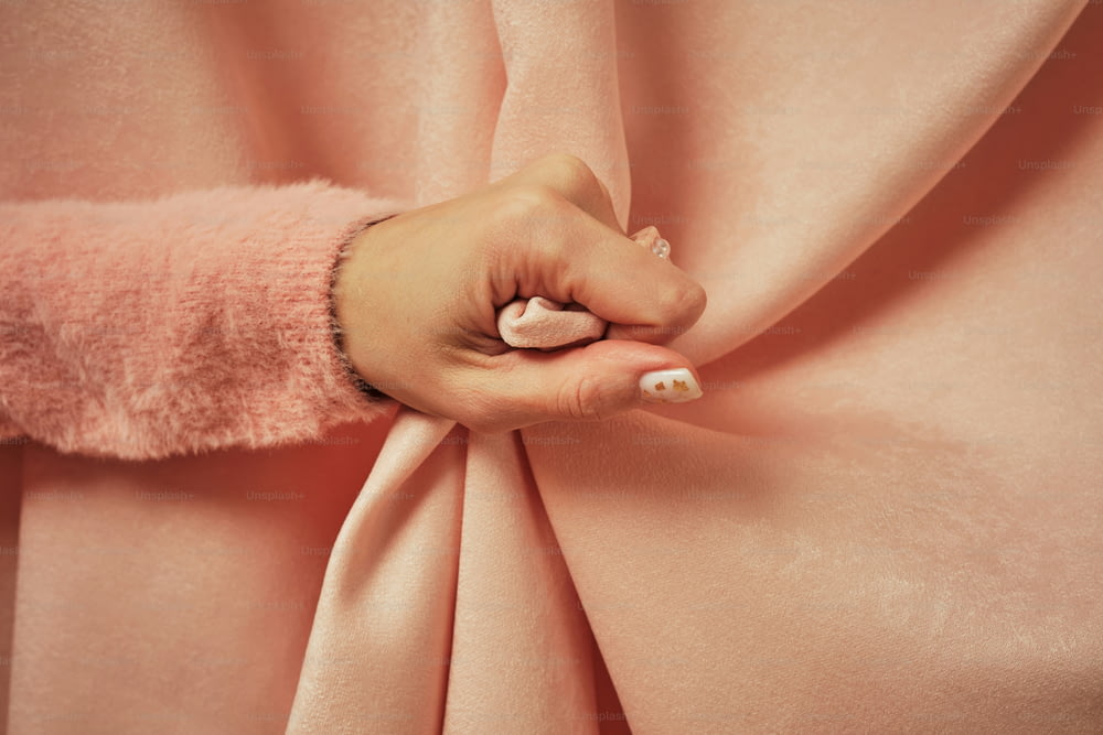 eine Frauenhand auf einem rosafarbenen Stoff