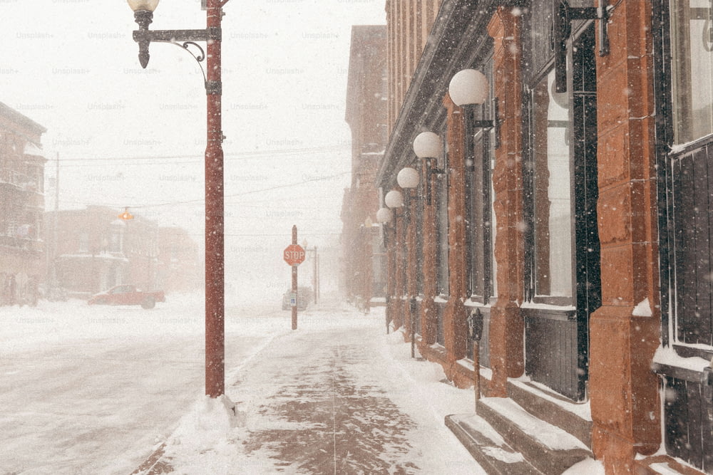 uma luz de rua em uma rua nevada com edifícios ao fundo