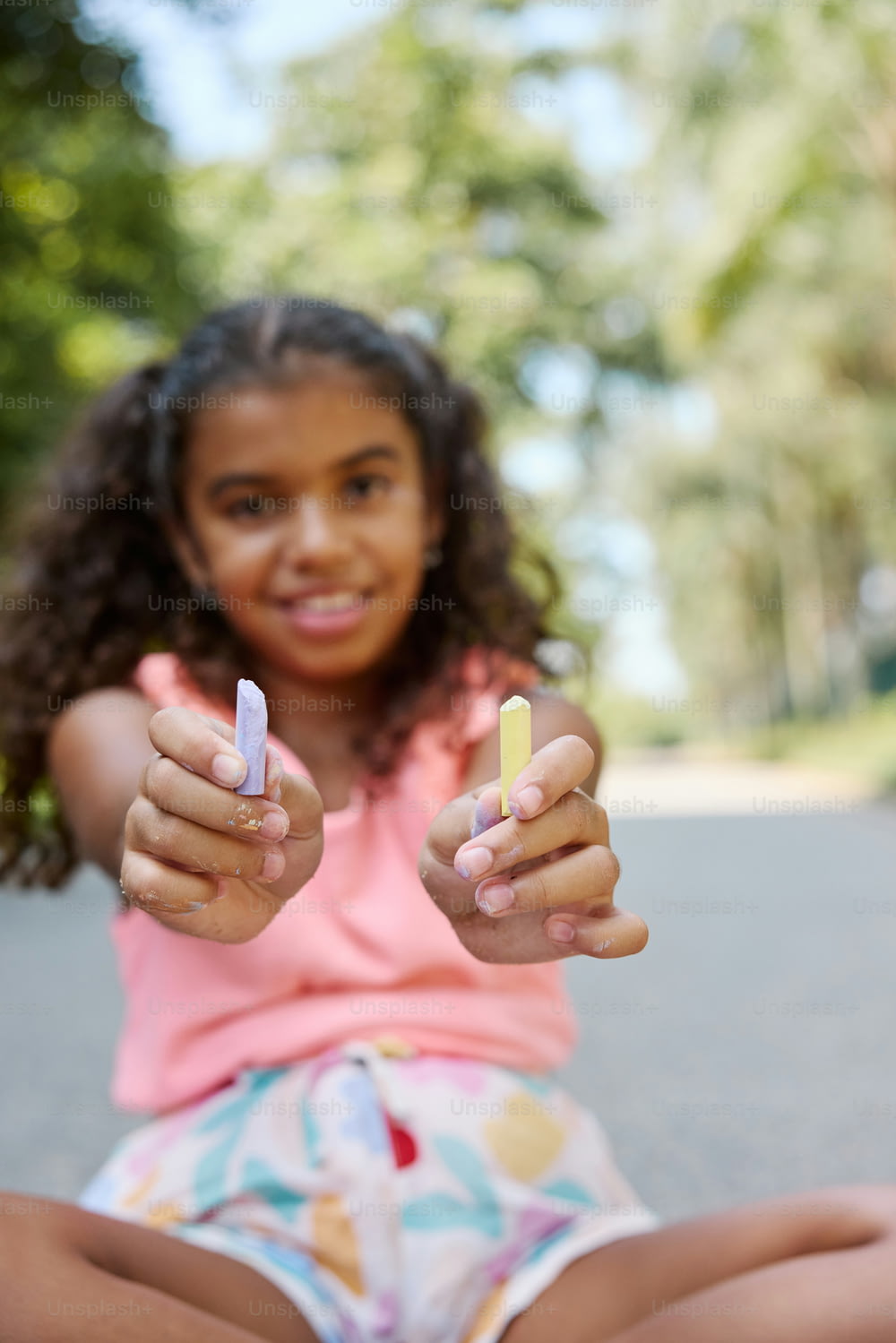 a young girl sitting on the ground holding up two fingers
