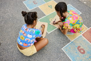 Dos muchachas sentadas en el suelo escribiendo números