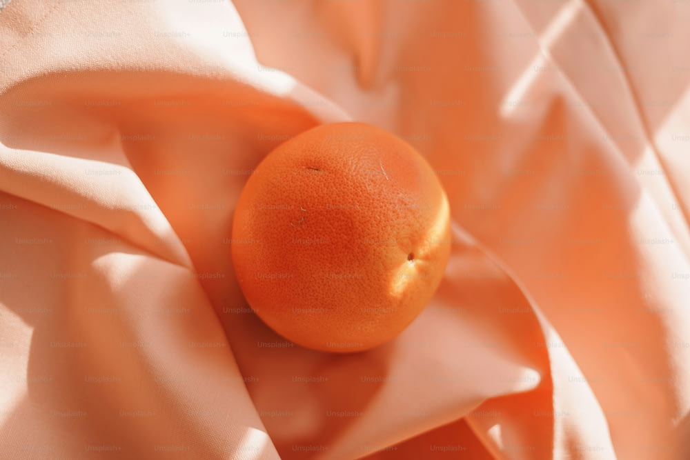 an orange sitting on top of a pink cloth