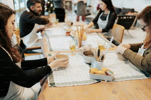 un groupe de personnes assises autour d’une table mangeant de la nourriture