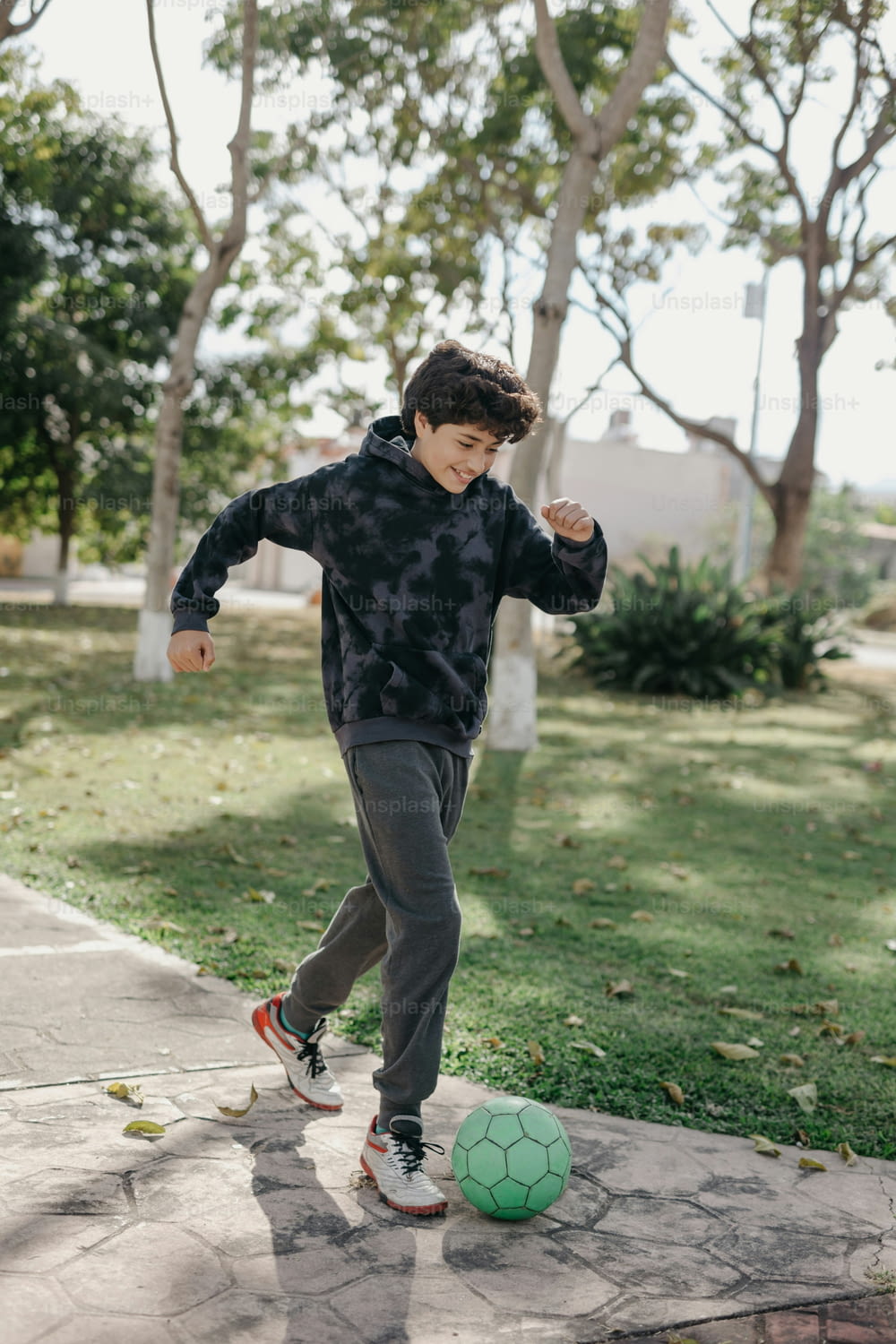 un ragazzo che calcia un pallone da calcio su un marciapiede