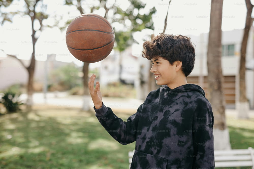 a young boy is spinning a basketball on his finger