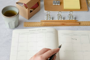 una persona che tiene una penna e scrive su un calendario