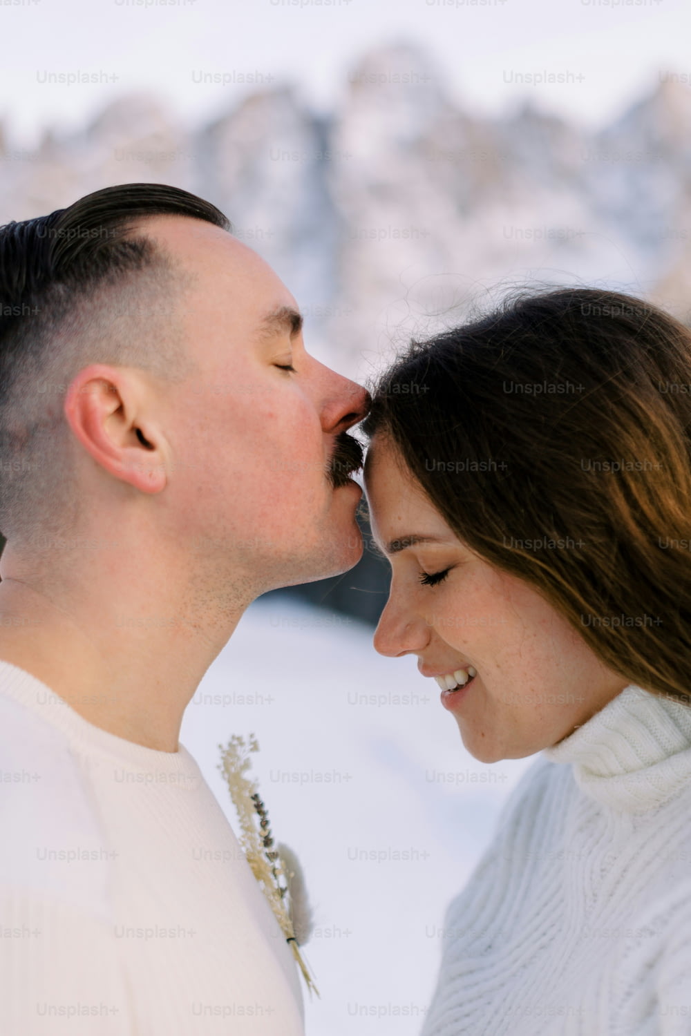 a man and a woman are kissing in the snow