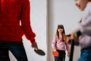 a young girl holding a ping pong paddle