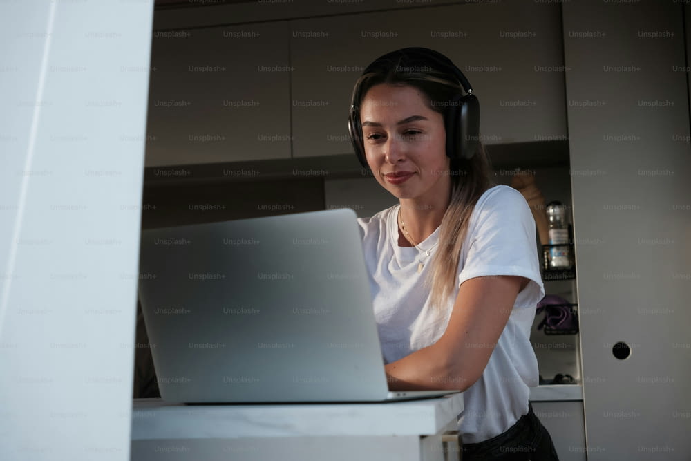 a woman with headphones on looking at a laptop