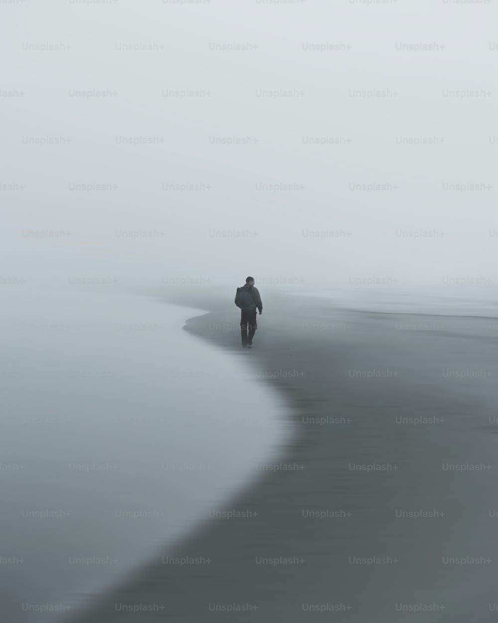 una persona che cammina su una spiaggia nella nebbia