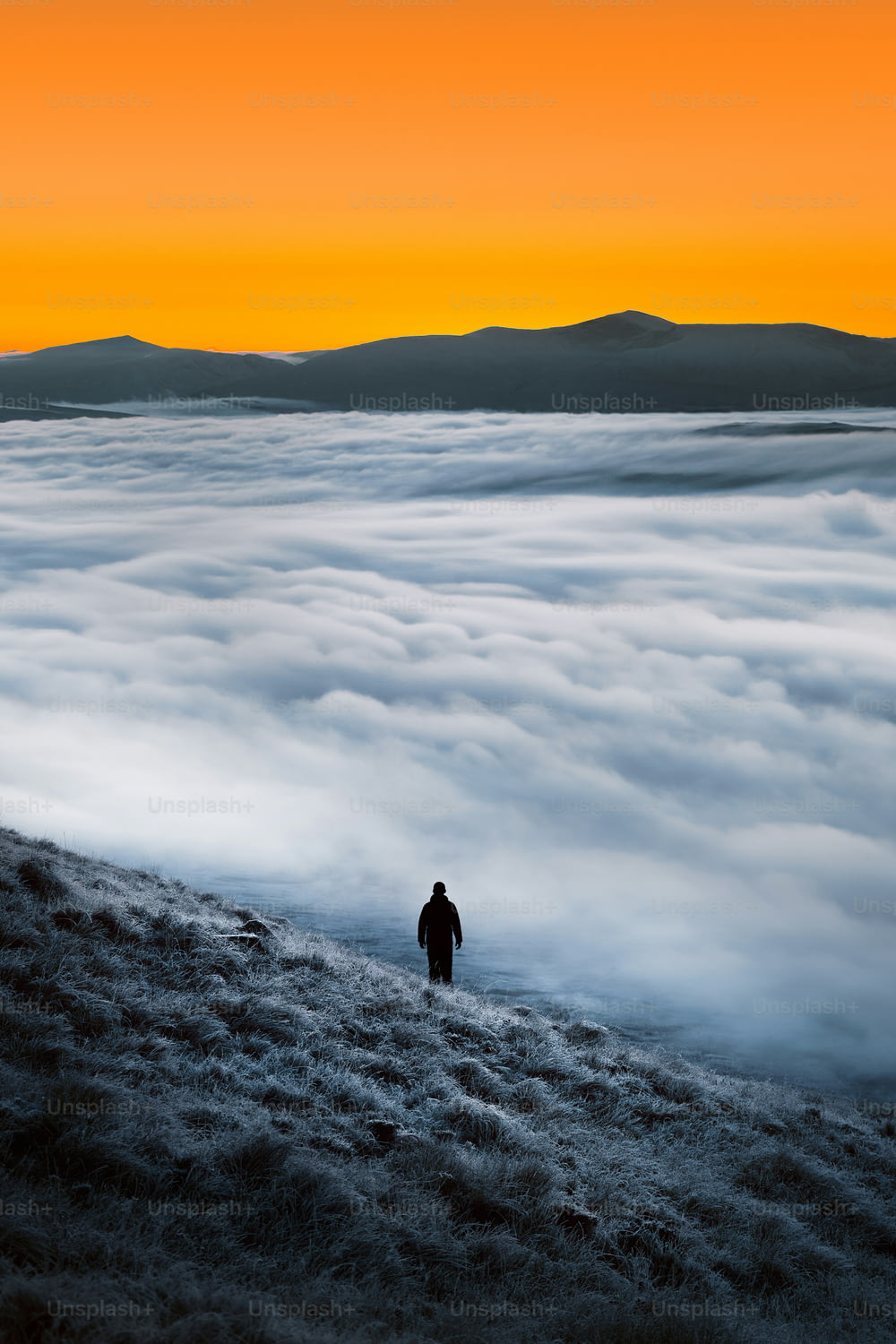a man standing on top of a hill surrounded by clouds