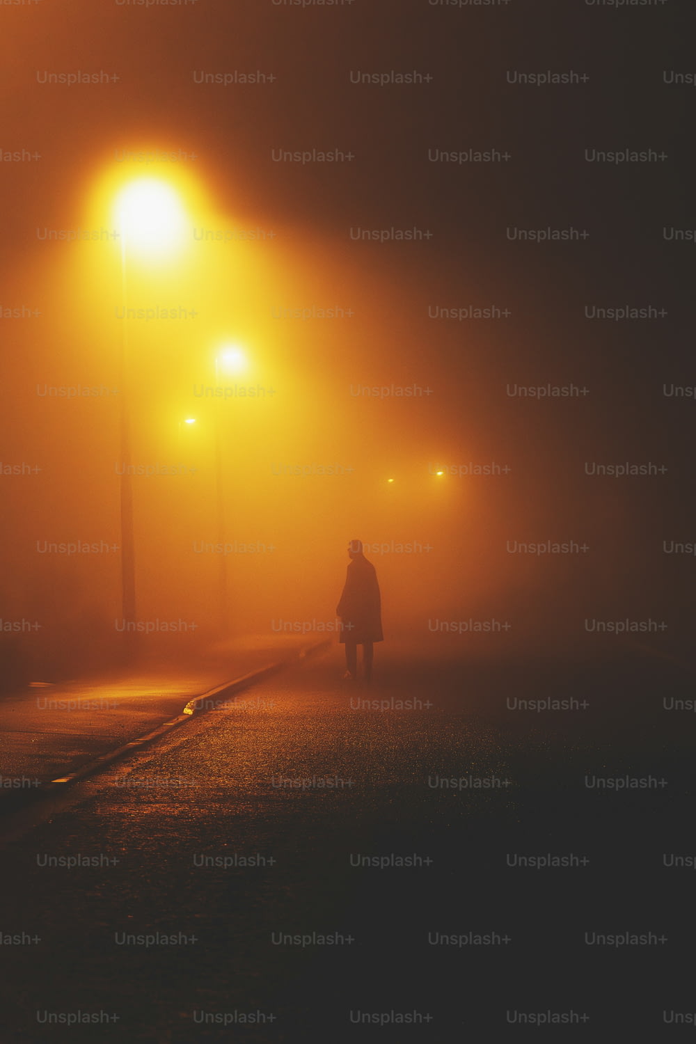 a person walking down a foggy street at night