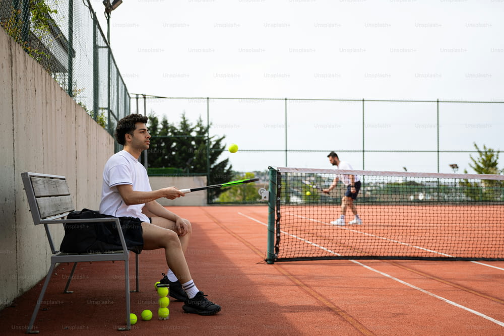a man sitting on a chair holding a tennis racquet