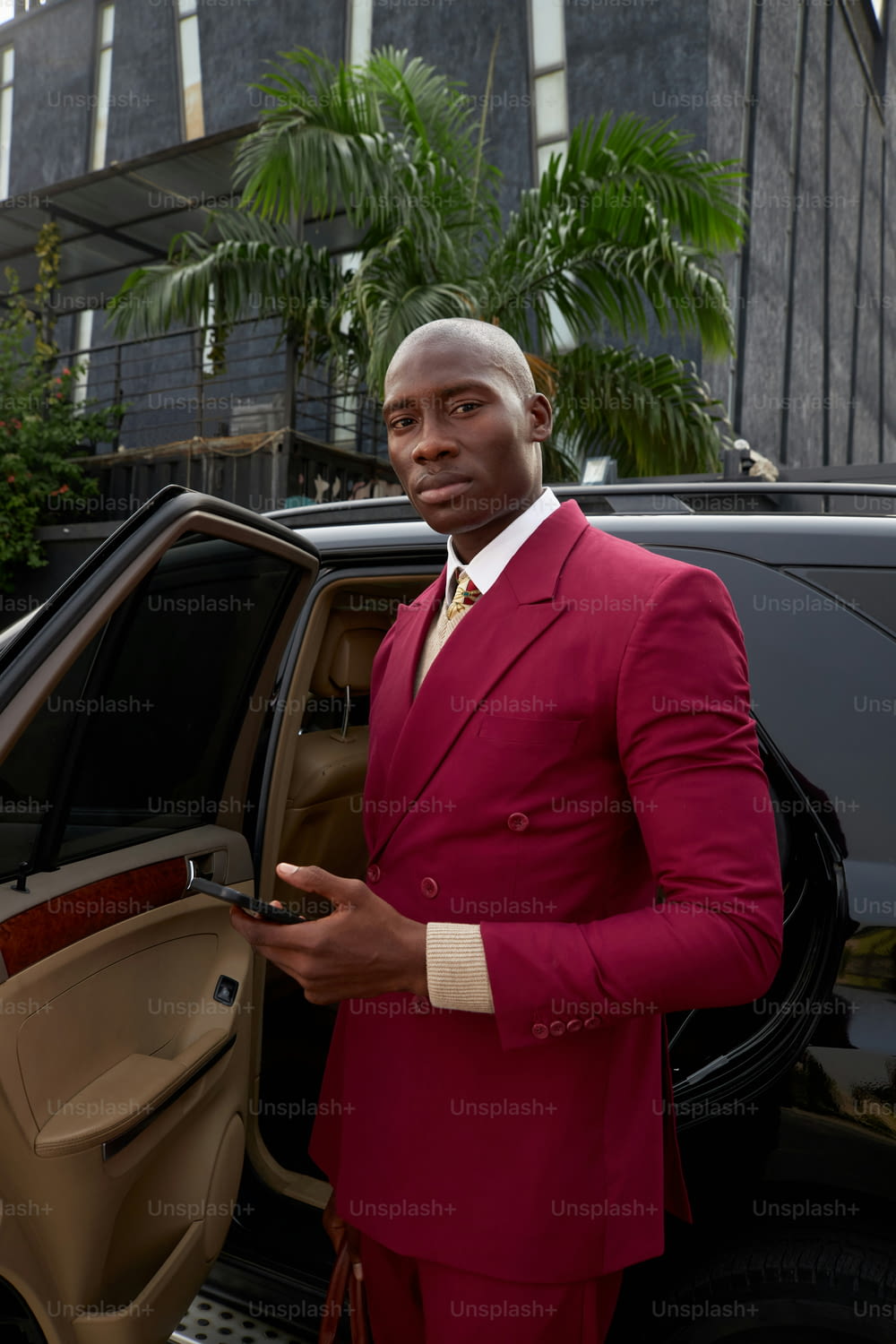 a man in a red suit standing next to a car