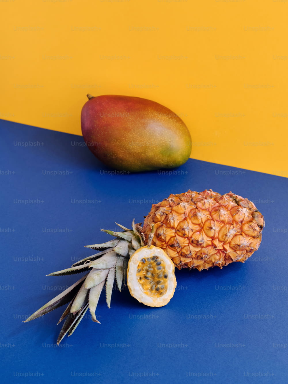 Un ananas e un mango su un tavolo blu