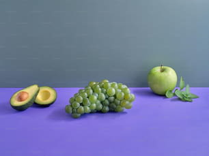 uma mesa roxa coberta com frutas verdes e um abacate