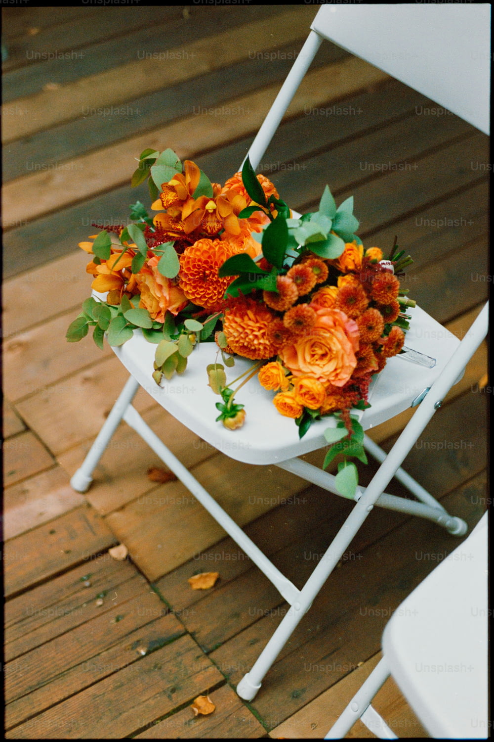 une chaise pliante blanche avec un bouquet de fleurs dessus