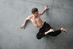 a shirtless man laying on the ground with his arms outstretched