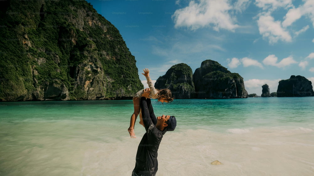 a man holding a woman on his shoulders while standing in the ocean