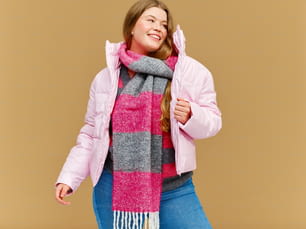 a woman wearing a pink jacket and a pink and grey scarf