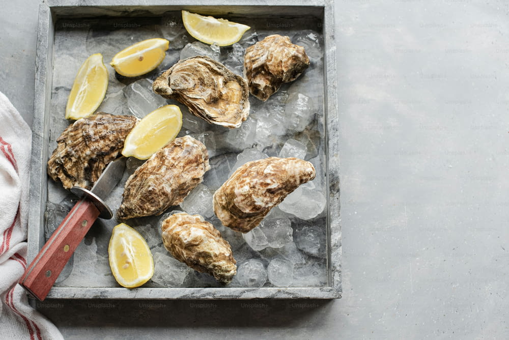 a tray filled with oysters and lemon wedges