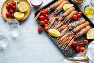 a tray of lobsters with lemons and tomatoes
