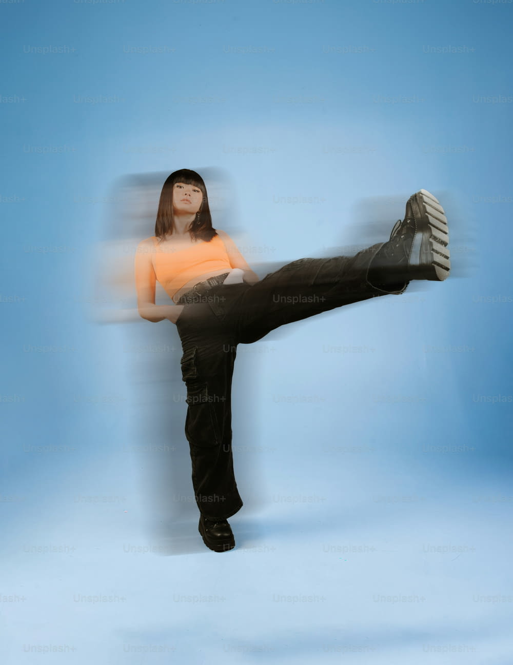 uma mulher de camisa laranja fazendo um chute