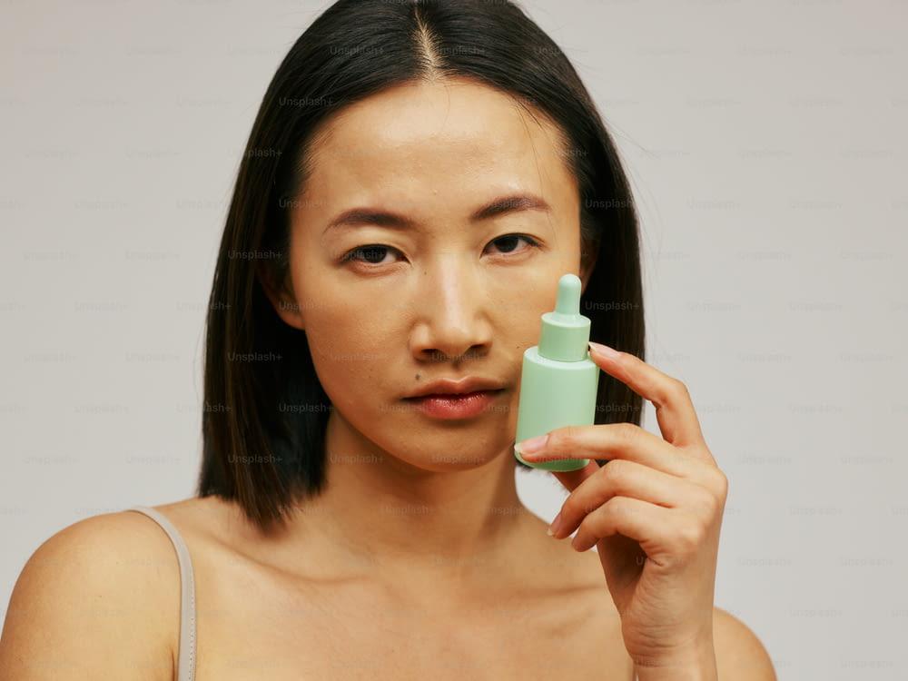 une femme tenant une bouteille de lotion devant son visage
