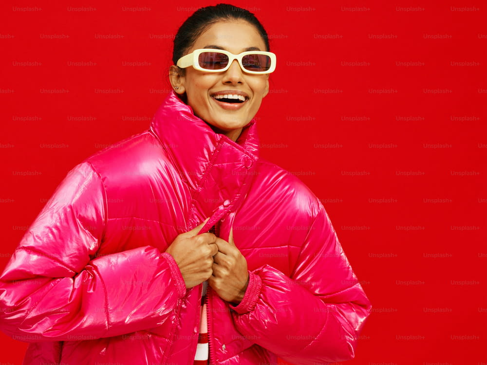 a woman in a bright pink jacket and sunglasses