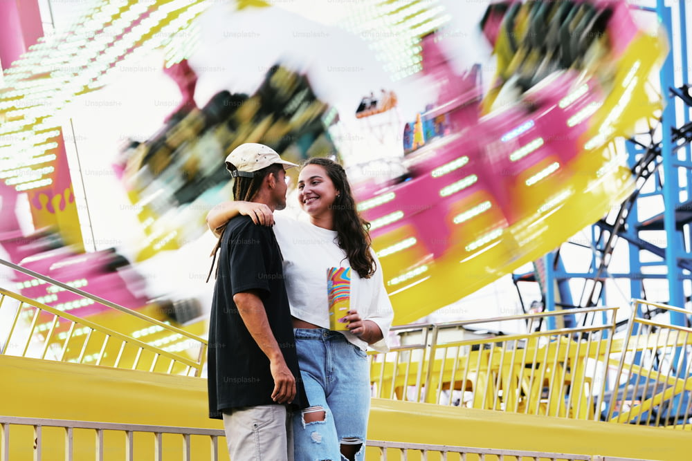 a man and a woman standing in front of a carnival ride