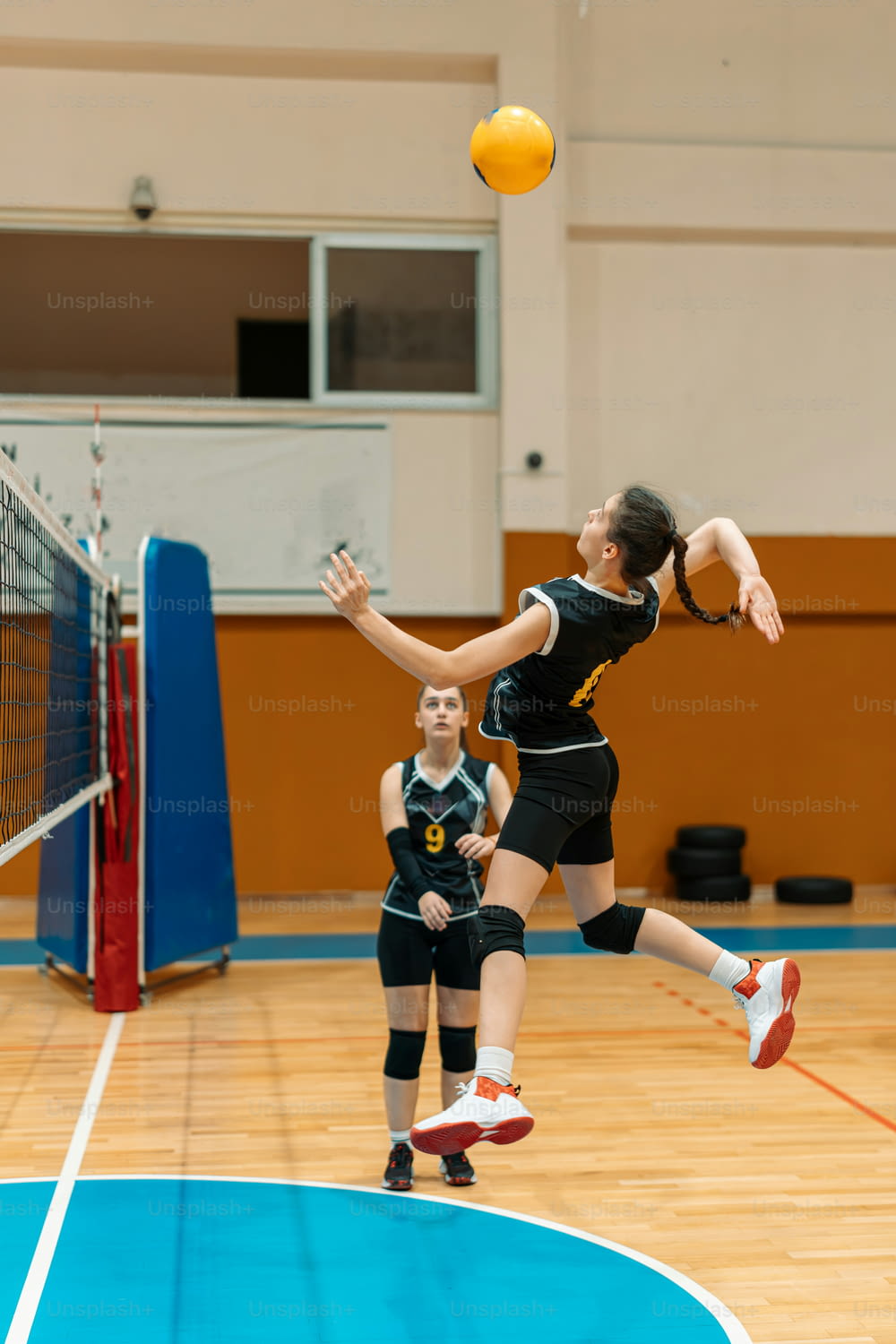 una mujer saltando para golpear una pelota de voleibol