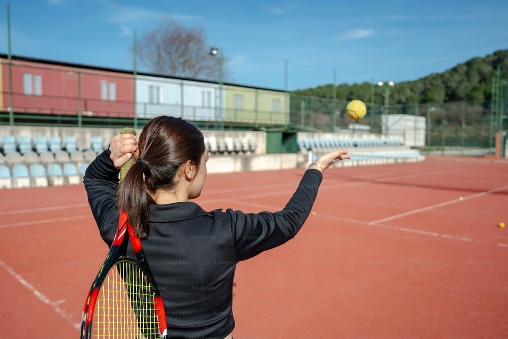 a woman holding a tennis racquet on top of a tennis court