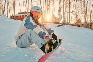 uma pessoa sentada na neve com uma prancha de snowboard