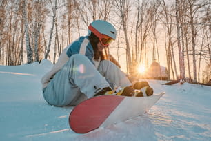 Un snowboarder está sentado en la nieve con su tabla