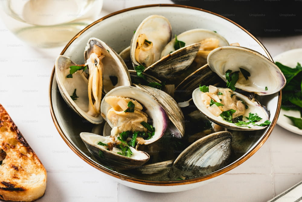 a bowl of clams with a slice of bread on the side