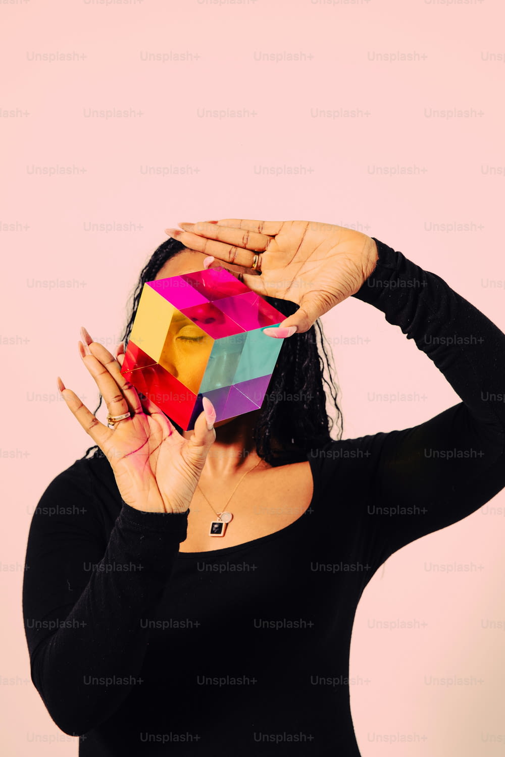 uma mulher segurando um cubo colorido na frente de seu rosto
