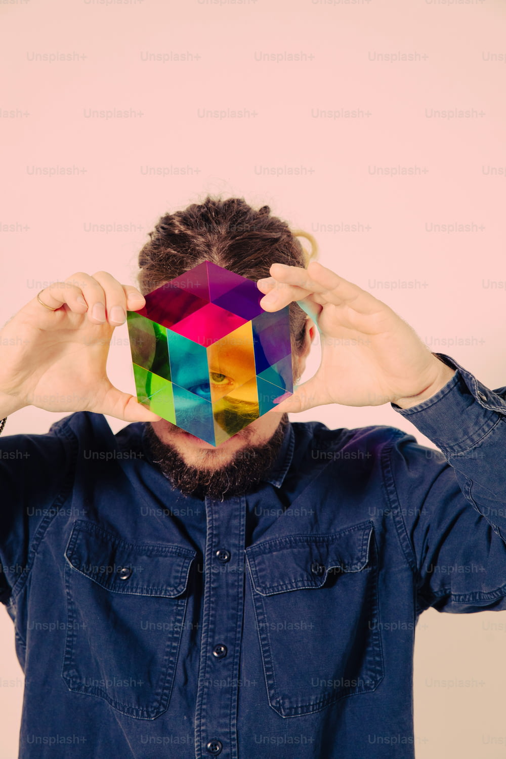 a man covering his face with a colorful cube