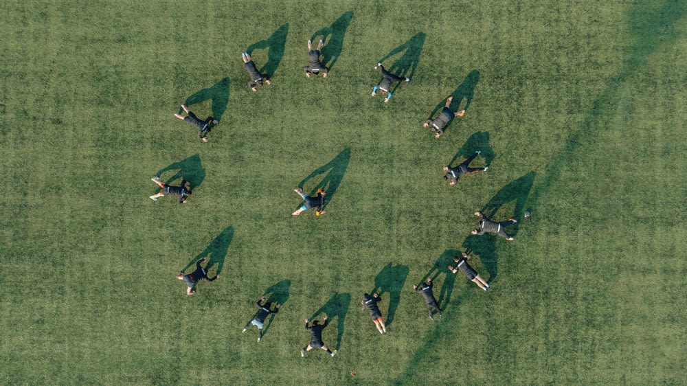 a group of people laying on top of a lush green field