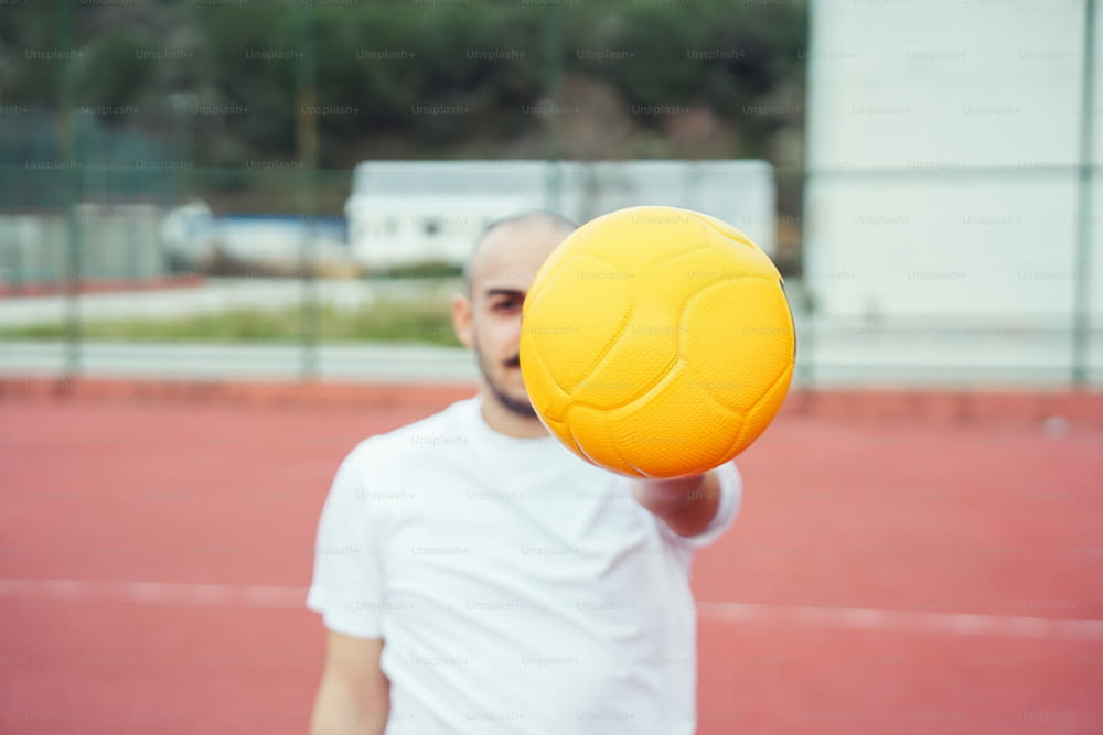 un uomo che tiene una palla gialla su un campo da tennis